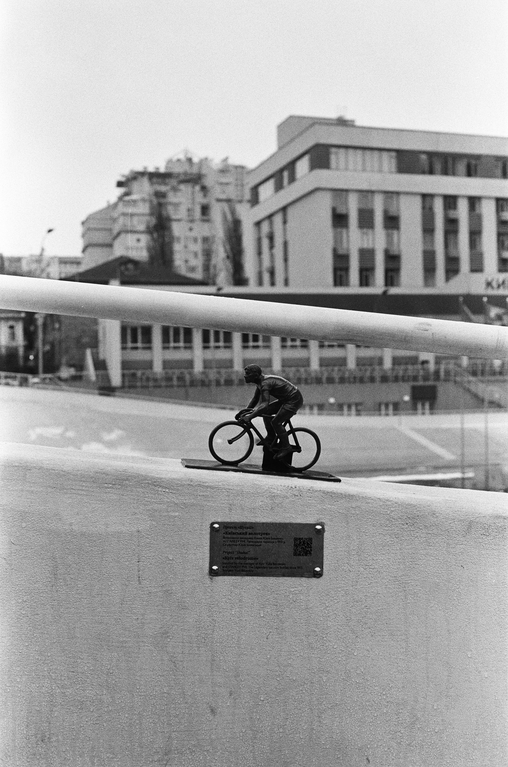 grayscale photo of man riding bicycle on road